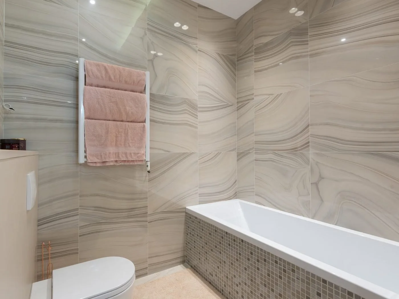 Bathroom repair Longview WA — finished grey marble-effect tiled bathroom with a panelled bath, chrome towel rail and toilet
